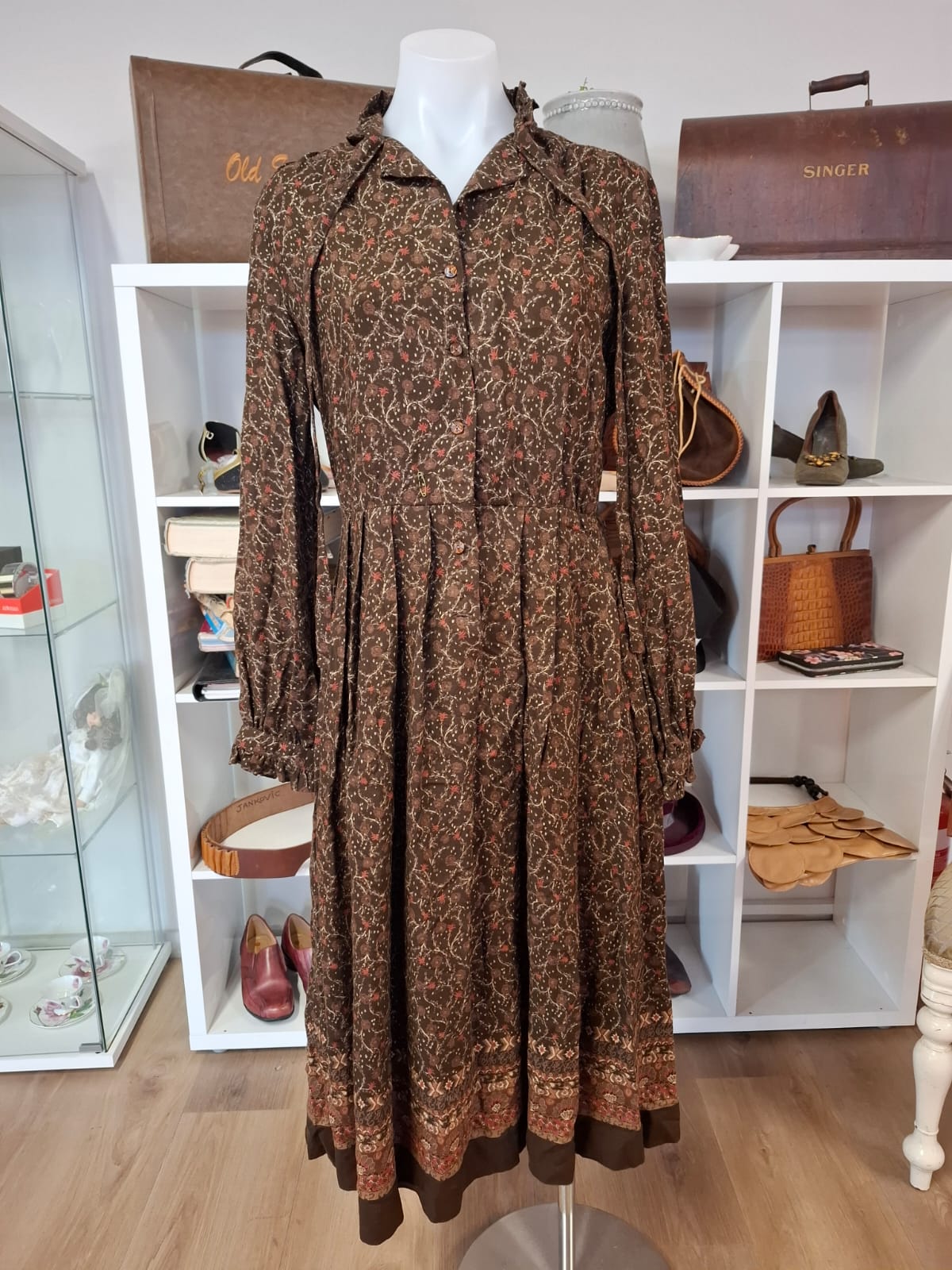 Damon International A division of LEON CUTLER Raffles necline design V-neck. LOng sleeves non stretch with tie on the neck part. Complete buttons down. Semi pleated skirts.