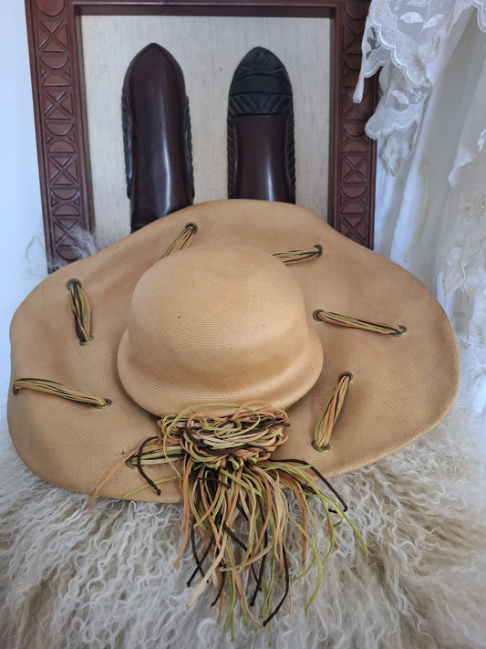 Ogilvie Natural Fibers & Earthy Flourish – With its wide curved brim, woven texture, and cascading green and brown ties, this beige beauty blends organic form with artful detail.