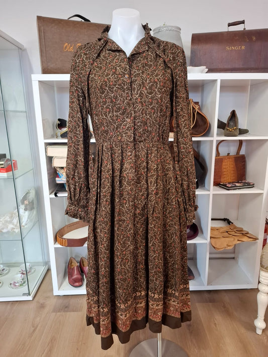 Damon International A division of LEON CUTLER Raffles necline design V-neck. LOng sleeves non stretch with tie on the neck part. Complete buttons down. Semi pleated skirts.