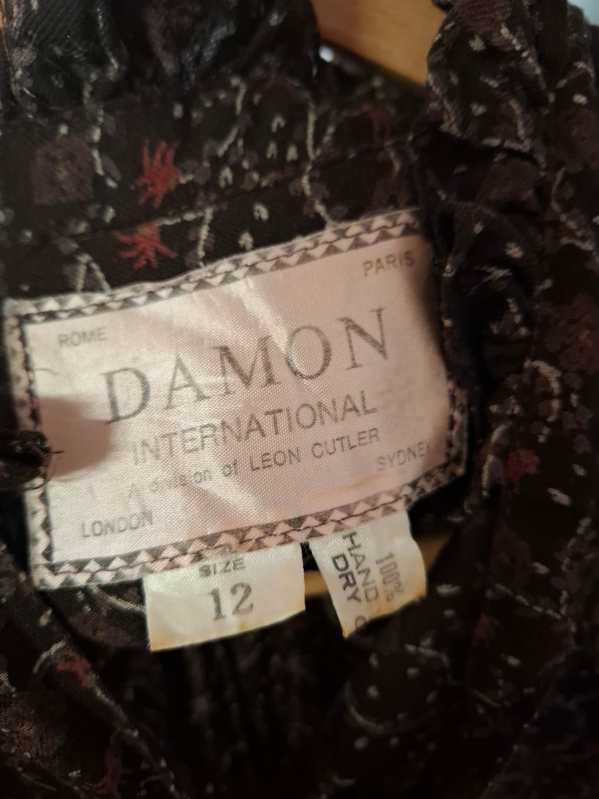 Damon International A division of LEON CUTLER Raffles necline design V-neck. LOng sleeves non stretch with tie on the neck part. Complete buttons down. Semi pleated skirts.