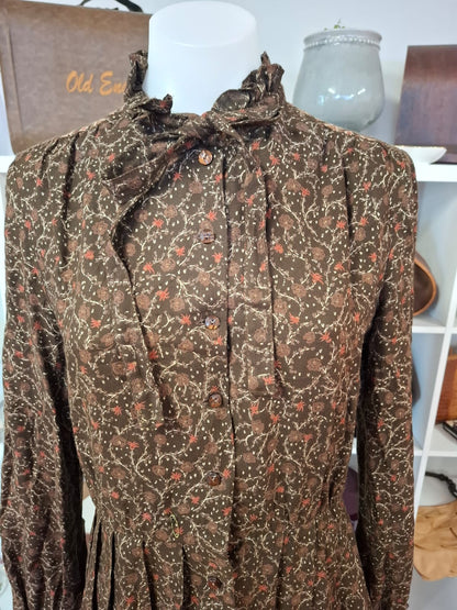 Damon International A division of LEON CUTLER Raffles necline design V-neck. LOng sleeves non stretch with tie on the neck part. Complete buttons down. Semi pleated skirts.