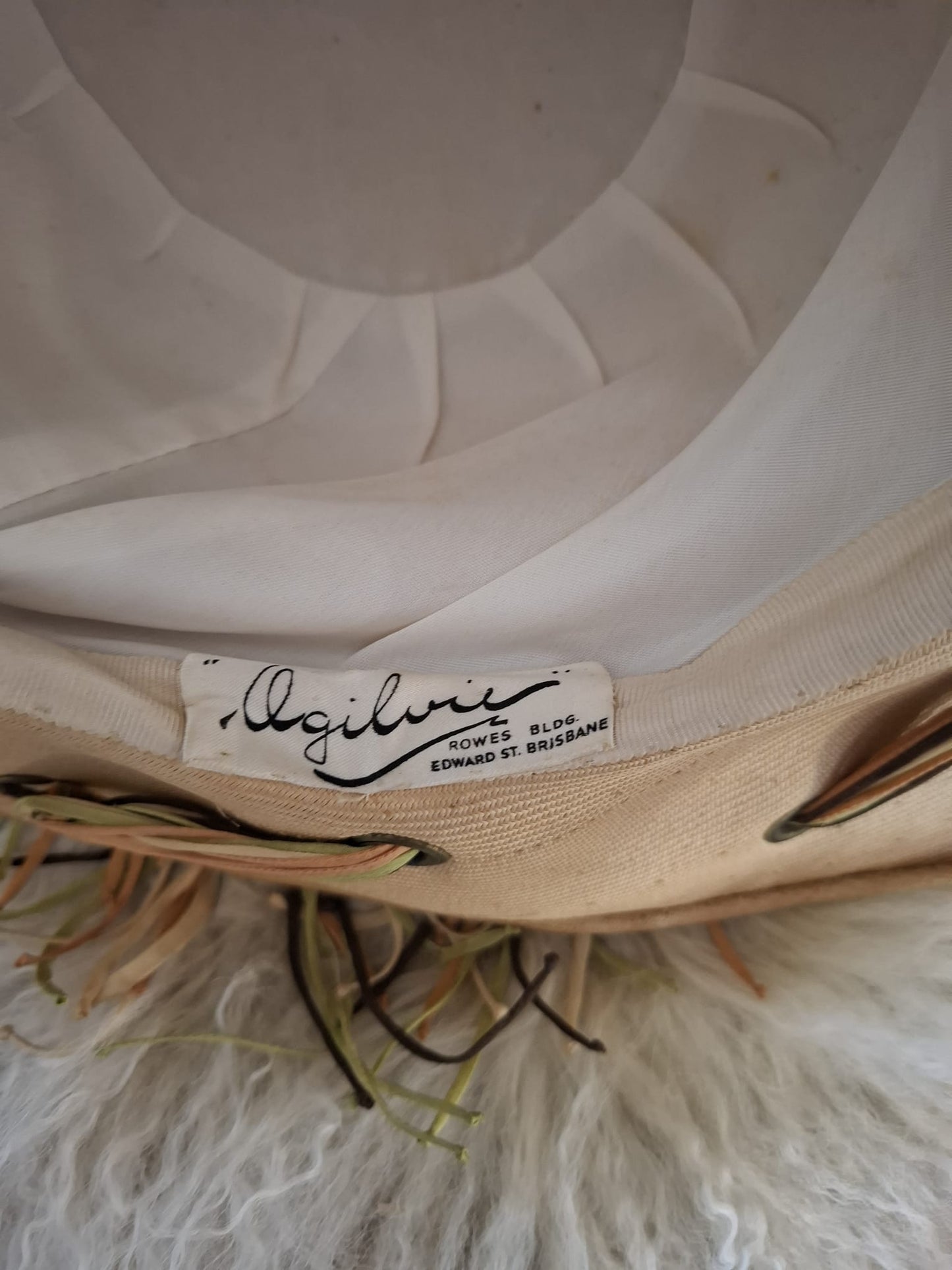 Ogilvie Natural Fibers & Earthy Flourish – With its wide curved brim, woven texture, and cascading green and brown ties, this beige beauty blends organic form with artful detail.