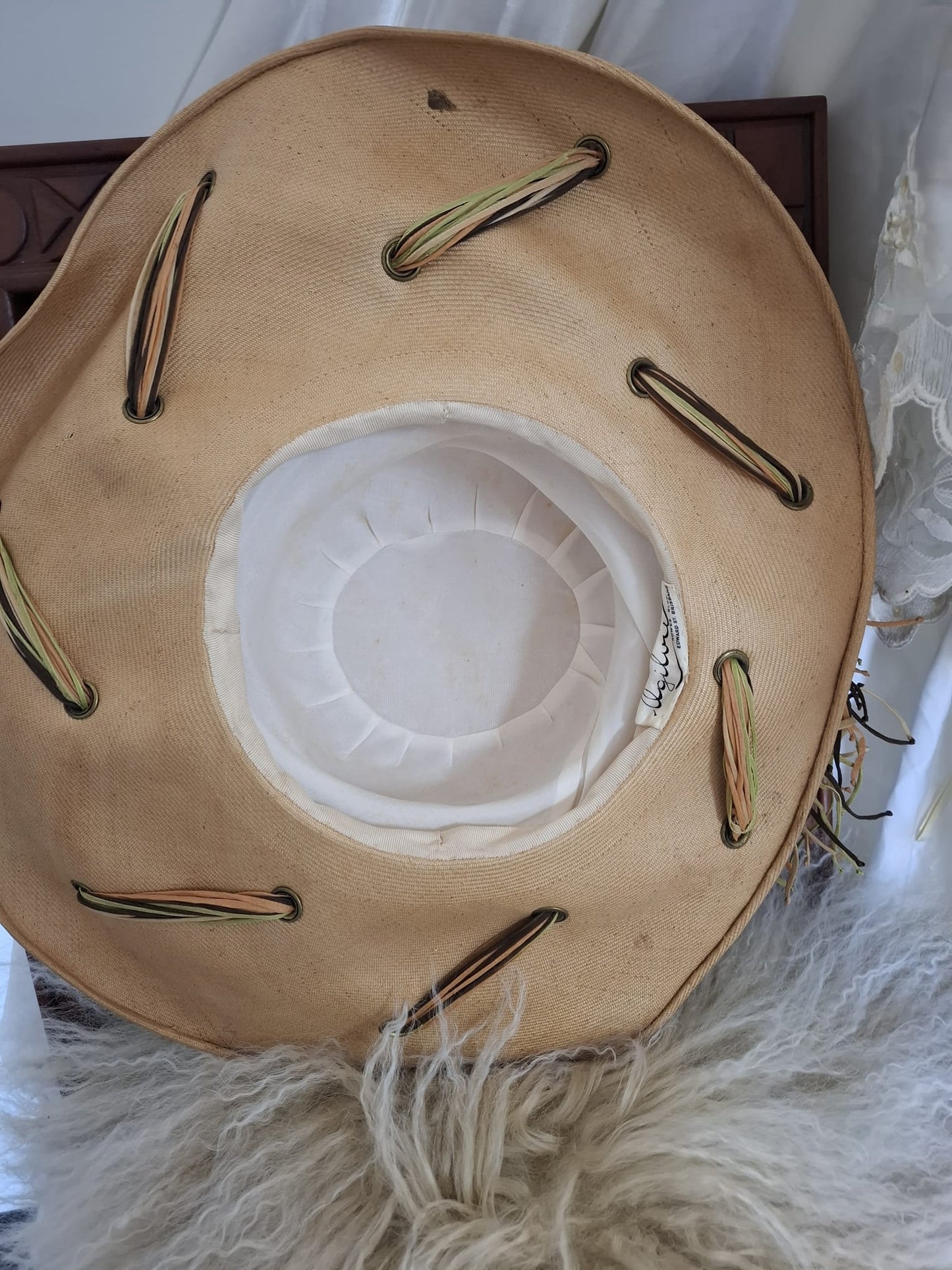 Ogilvie Natural Fibers & Earthy Flourish – With its wide curved brim, woven texture, and cascading green and brown ties, this beige beauty blends organic form with artful detail.