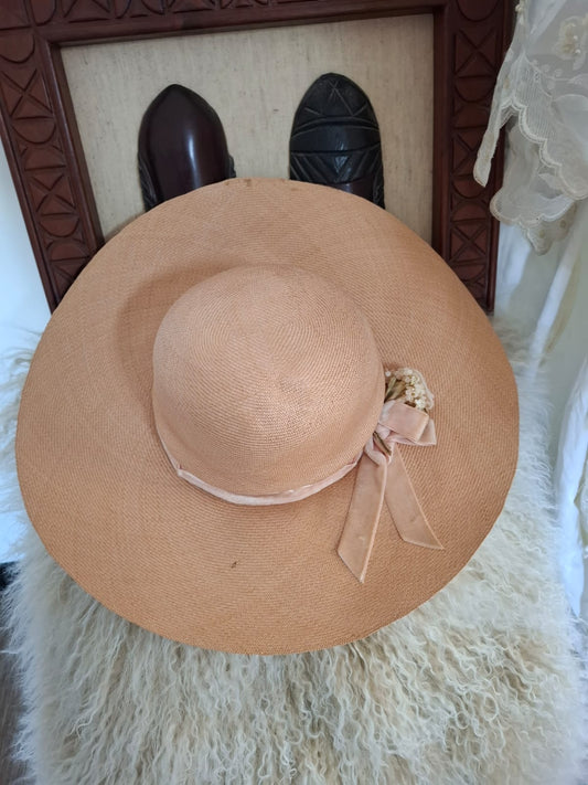 Designed By Goullet of Melbourne Breezy Elegance- Featuring a sweeping brim and tall crown, this airy piece is adorned with a soft bow, floral accents, and delicate trims, capturing breezy elegance with a touch of whimsy.